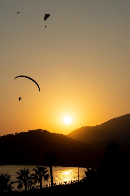 sunset in Oludeniz with the landscape of the sea and silhouettes of people flying in paragliding