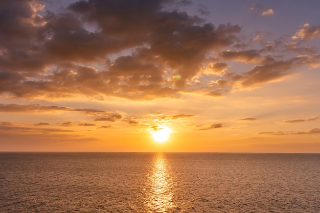 Sunset reflection ocean. beautiful sunset behind the clouds and blue sky above the over ocean landscape background