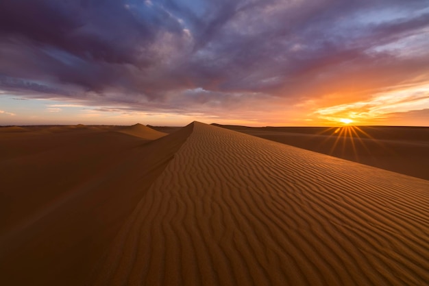 Sunset over the sand dunes in the desert Arid landscape of the Sahara desert