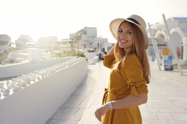 Sunset in Santorini Romantic attractive young woman turns around and looking at camera in Santorini Greece