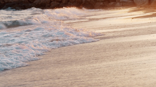 Sunset scene of foamy sea waves rolling in on the shore