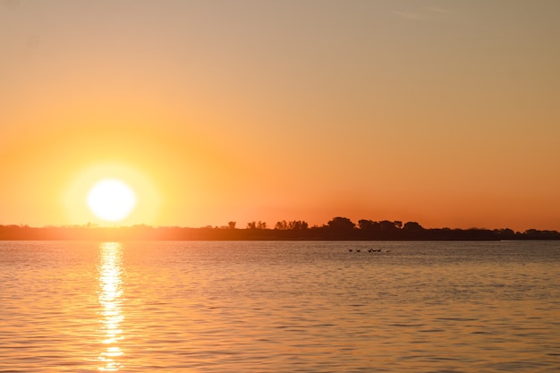 Sunset on the sea with a few birds flying.