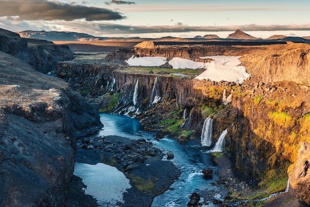 Sunset over Sigoldugljufur with tiny waterfall flowing in canyon on Icelandic Highlands in summer at Iceland