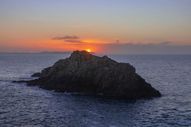 Sunset over small rock island in the sea