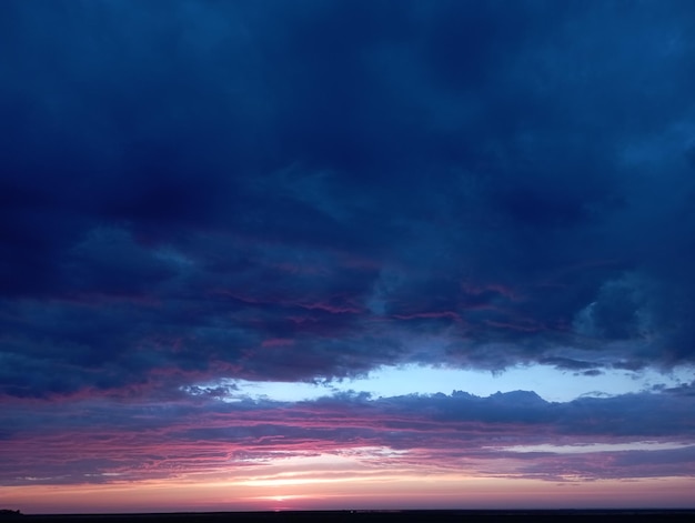 Sunset or sunrise in a spring field with green grass, willow trees and cloudy sky. Sunbeams making