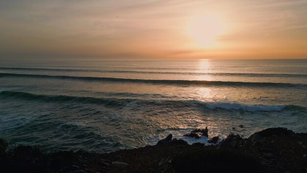 Sunset volcanic beach silhouette at sea coastline marine shore foaming waves