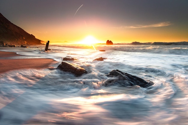 Sunset while sea waves hitting the rocks on the beach at Ilbarritz beach in Biarritz Basque Country