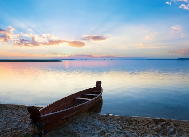 Sunset with boat near the summer lake shore