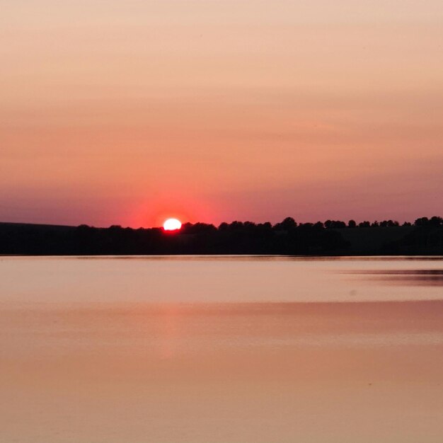 A sunset with the sun setting behind the trees