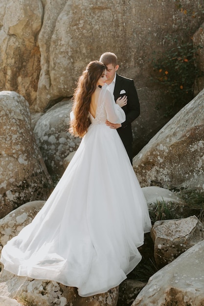 Sunshine portrait of happy bride and groom outdoor in nature location at sunset. Warm summertime