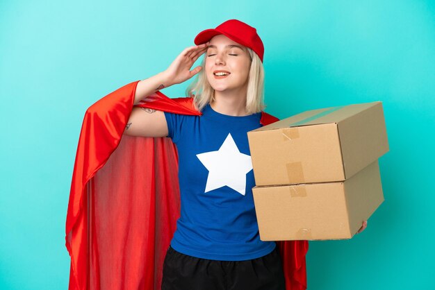 Super Hero caucasian delivery woman isolated on blue background smiling a lot