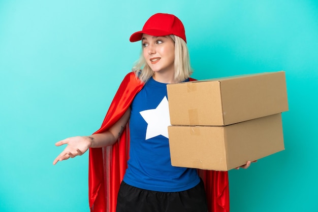 Super Hero caucasian delivery woman isolated on blue background with surprise expression while looking side