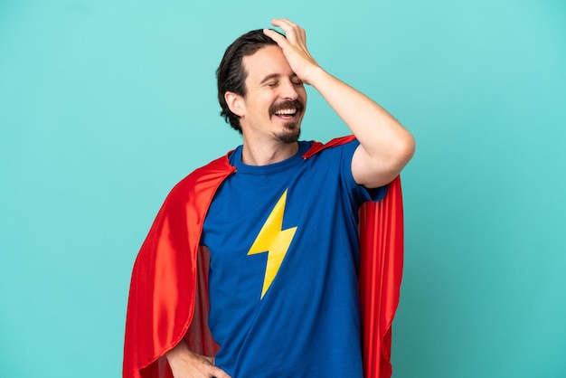 Super Hero caucasian man isolated on blue background smiling a lot