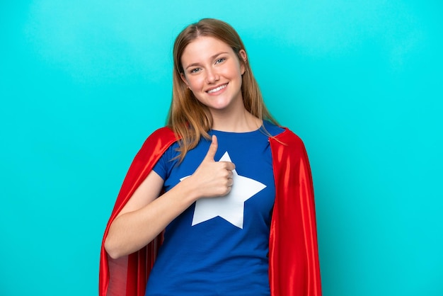 Super Hero caucasian woman isolated on blue background giving a thumbs up gesture