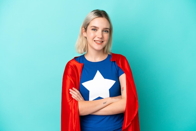 Super Hero caucasian woman isolated on blue background keeping the arms crossed in frontal position