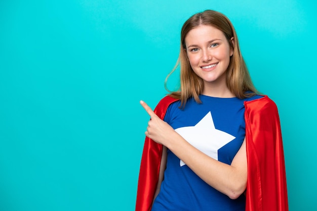 Super Hero caucasian woman isolated on blue background pointing to the side to present a product