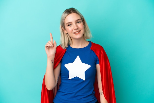 Super Hero caucasian woman isolated on blue background showing and lifting a finger in sign of the best