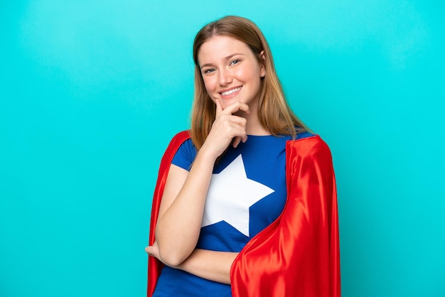 Super Hero caucasian woman isolated on blue background smiling