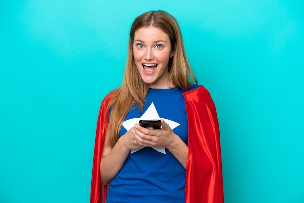 Super Hero caucasian woman isolated on blue background surprised and sending a message