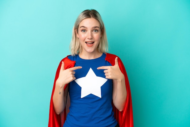 Super Hero caucasian woman isolated on blue background with surprise facial expression