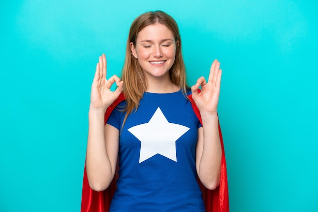 Super Hero caucasian woman isolated on blue background in zen pose