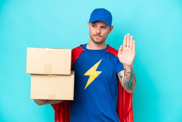 Super Hero delivery man over isolated background making stop gesture and disappointed