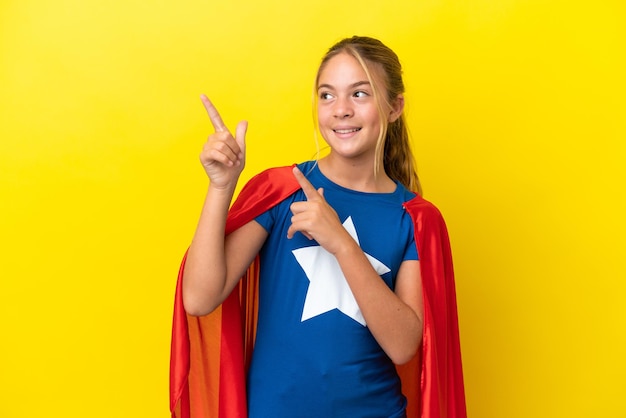 Super Hero little girl isolated on yellow background pointing with the index finger a great idea