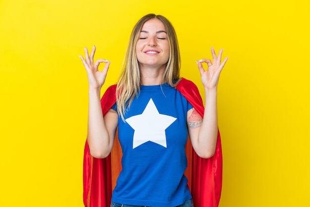 Super Hero Romanian woman isolated on yellow background in zen pose