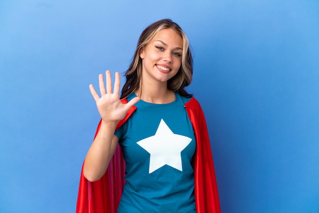 Super Hero Teenager girl isolated on blue background counting five with fingers