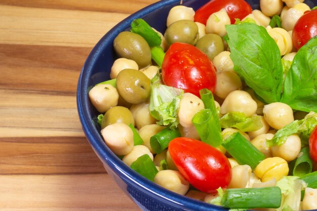 Superclose of chickpeas with leaves olives and tomatoes in two bowls on the table