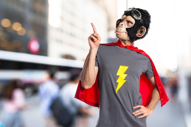 Superhero monkey man pointing up on unfocused background