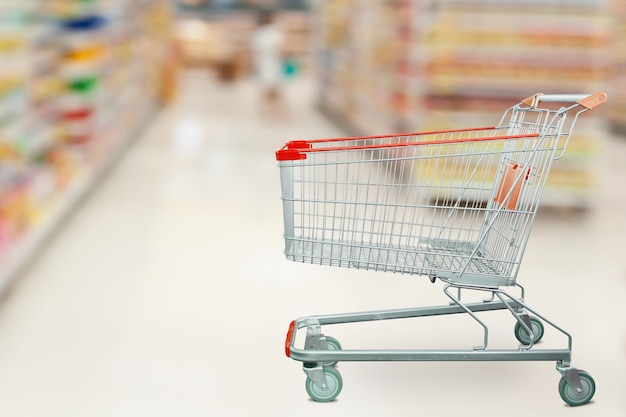 Supermarket aisle with empty shopping cart at grocery store retail business concept