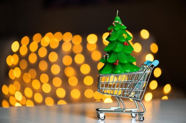 Supermarket basket with green candle christmas tree on bokeh lights background