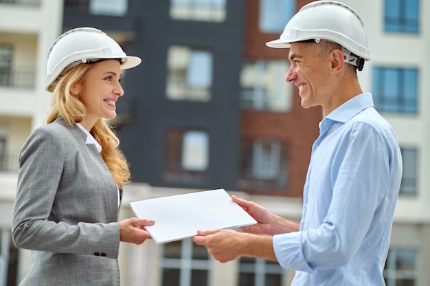 Supervisor handing over the building documentation to a joyous worker