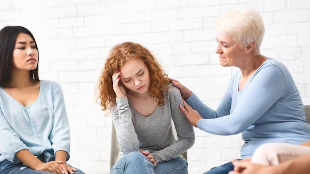 Photo support group female psychologist supporting depressed girl during group therapy indoor selective