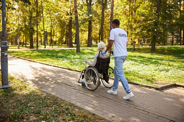 supportive volunteer getting a retired old lady out of the park