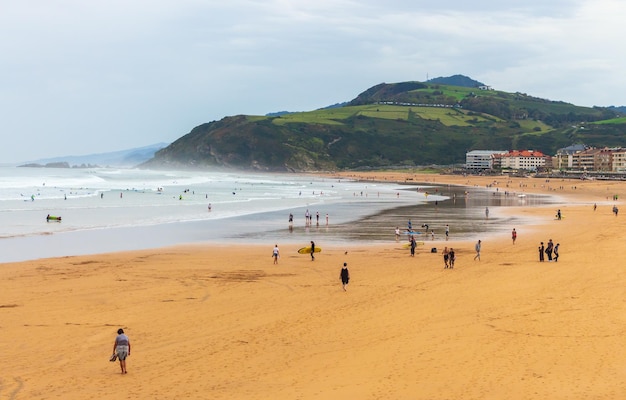 Surf beach with tourists Basque country Spain Surfers on wide beach with mountain Active people