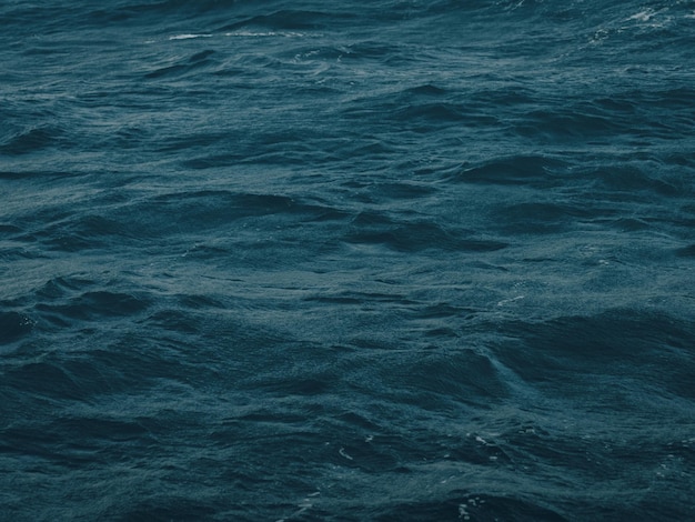 Surface of dark blue water abstract texture of sea with waves in low light