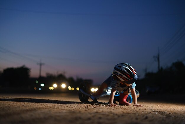 Photo surface level of boy fallen from bicycle on road at night