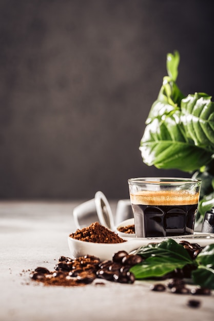 surface with glass cup of coffee, coffee beans and leafs. Beverage cafe shop concept with copy space