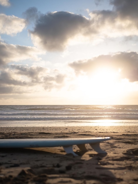 A surfboard lying on the beach at sunrise