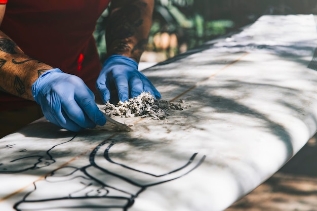 Surfer cleaning his surfboard Remove old wax with a wax comb Get ready to surf Surfing lifestyle