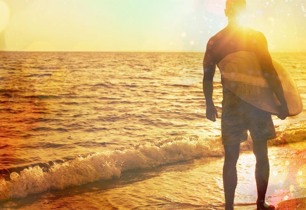 Surfer on the ocean beach at sunset