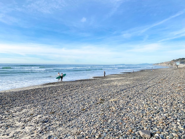 Surfer walking with their boards on Torrey Pines State Beach before sunset twilight