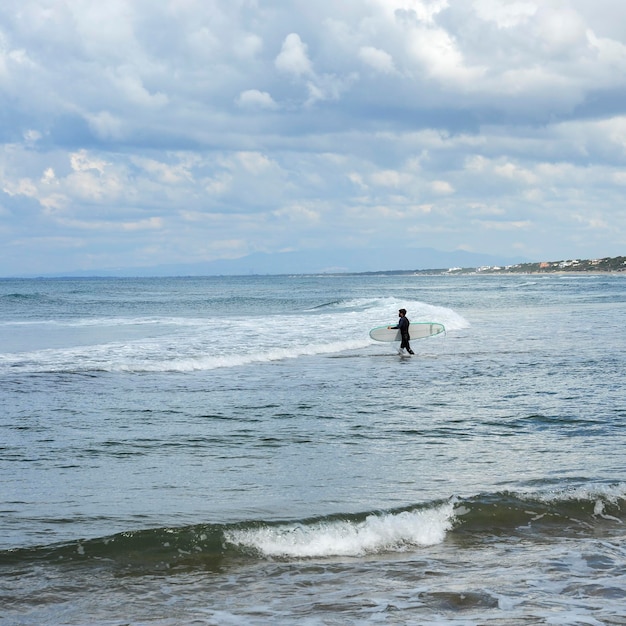 Surfer with the wetsuit diving in blue sea with his surfboard