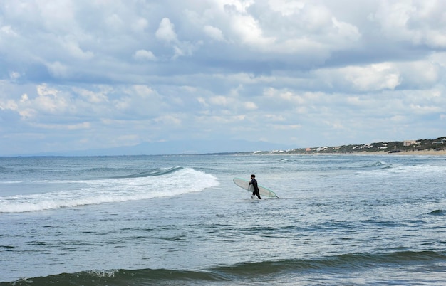 Surfer with the wetsuit diving in blue sea with his surfboard