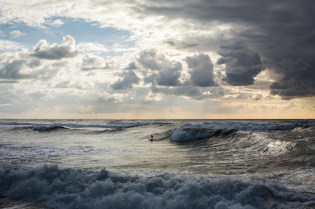 Surfers ride the sea waves at sunset