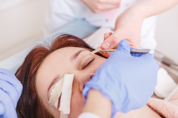 Surgeon applies a bandage to the female patient's eyelids after 