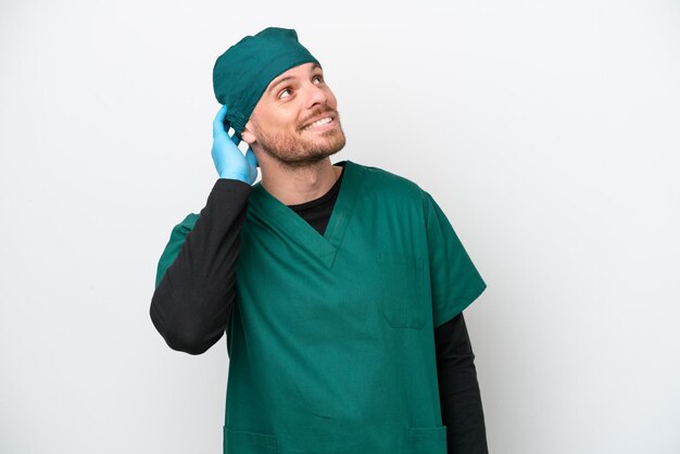 Surgeon Brazilian man in green uniform isolated on white background thinking an idea