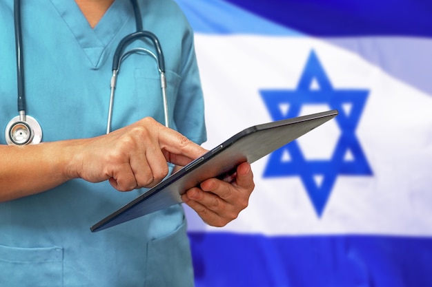 Surgeon or doctor using a digital tablet on the background of the Israel flag